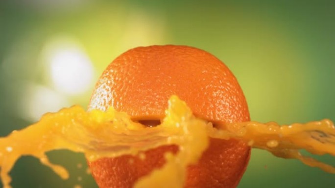 新鲜橙色水果在绿色自然背景4K慢动作中喷出并爆裂果汁