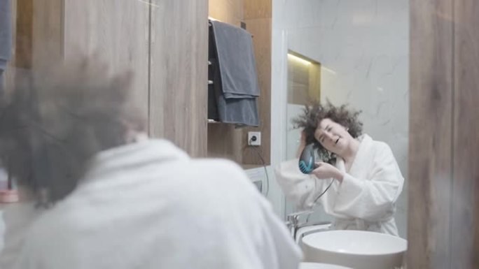 年轻女子在酒店浴室唱歌吹干头发，享受早晨