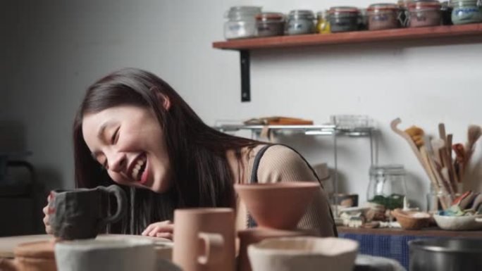 年轻女子在陶器工作室用粘土覆盖和装饰陶瓷。波特女孩在烤粘土上画颜色。教育、商业、艺术天赋和创意手工制