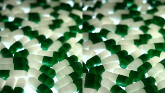 垂直: 绿色和白色胶囊药丸旋转，黑色照明