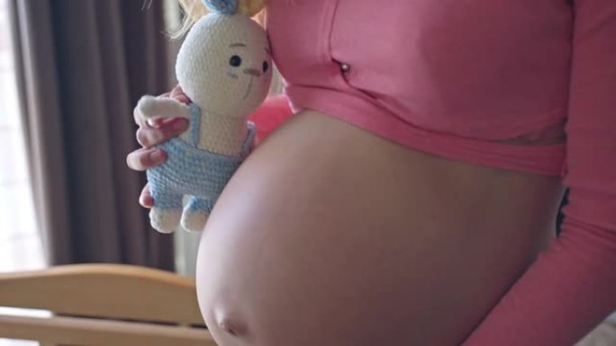 孕妇玩针织兔子玩具，抚摸她怀孕的肚子