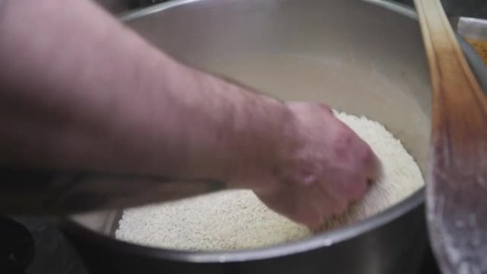 厨师用手手动搅拌一锅米饭的细节镜头