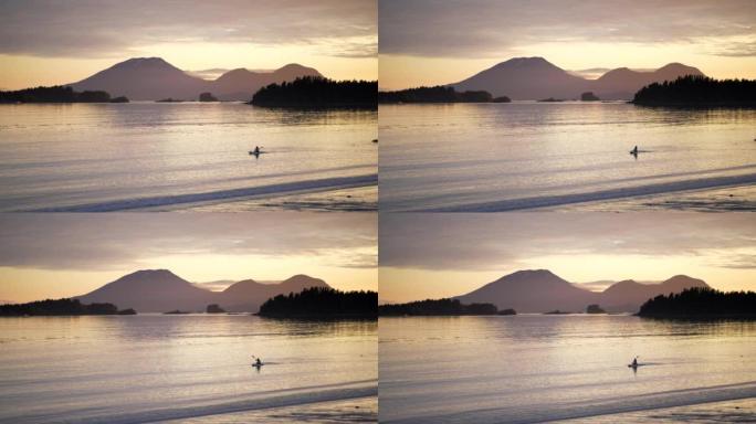 日落时海湾岸边的皮划艇运动员的远景