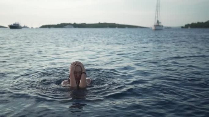 日落时在海湾游泳的年轻女子