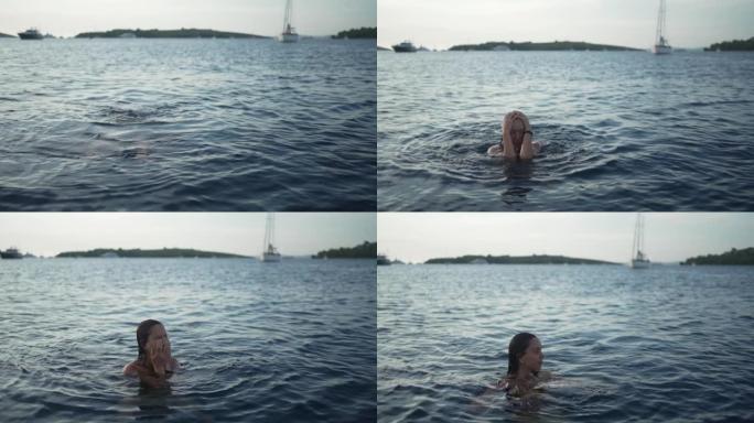 日落时在海湾游泳的年轻女子