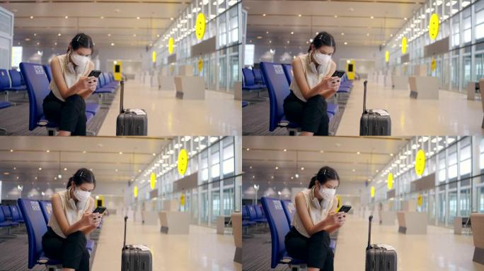 亚洲妇女在机场出发区使用数字平板电脑戴口罩。