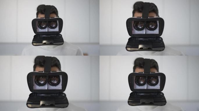 开放式VR耳机中开朗的年轻中东男人的棕色眼睛。有趣的无忧无虑快乐的家伙在周末在家室内玩增强现实模拟。