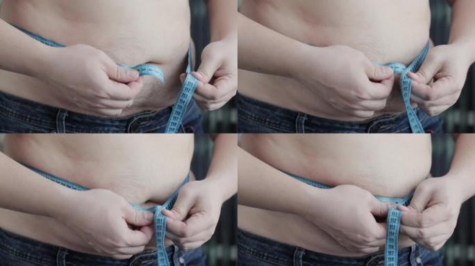 一个男人用卷尺测量他肥胖的大肚子，特写镜头。超重问题，肥胖。慢动作