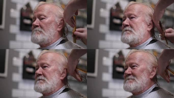 理发店，英俊的老年型男与灰色的胡子在理发店用剪刀理发，特写