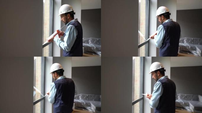 拉丁美洲建筑工人安装窗户并涂上硅酮密封胶