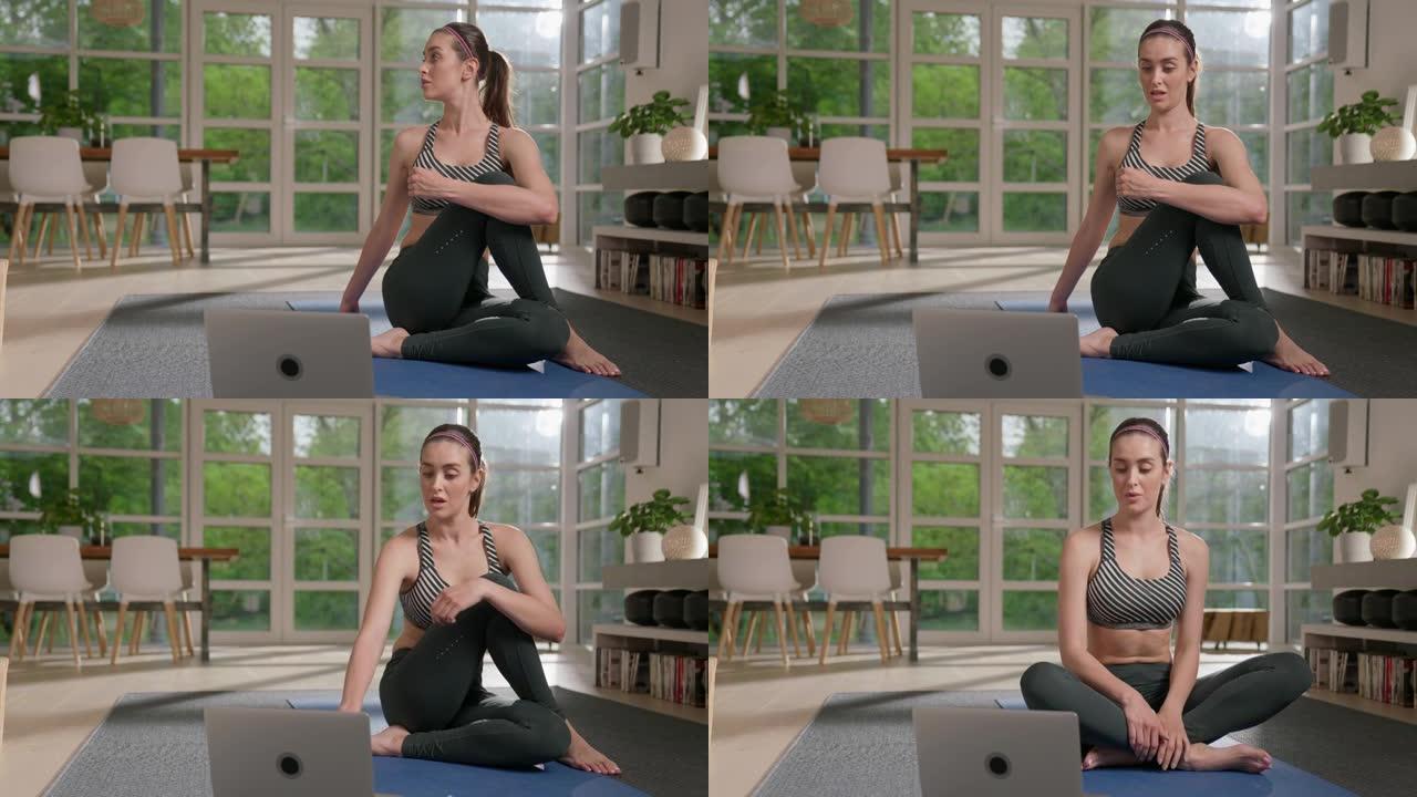 女运动员用笔记本电脑在瑜伽垫上做脊柱扭转。放松的家庭锻炼