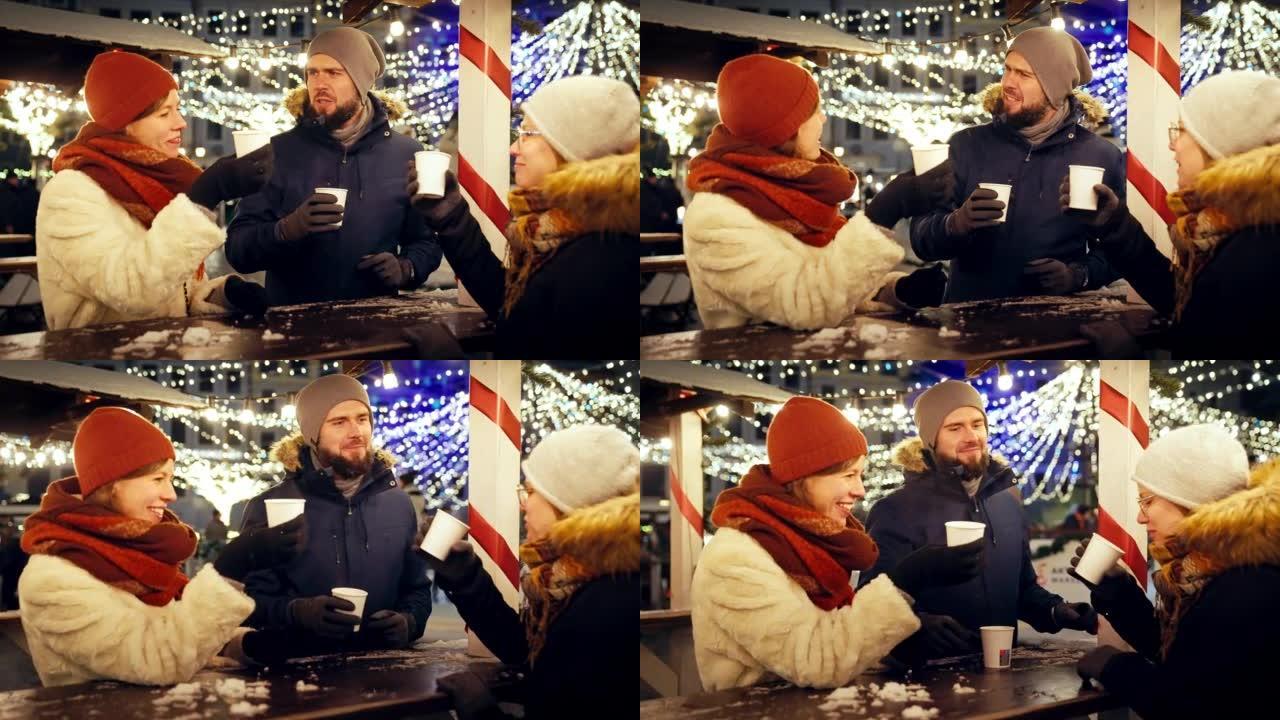 一群朋友在慢动作的下雪的圣诞节夜晚一起用热巧克力敬酒
