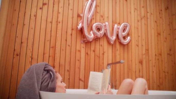 女人在现代简约浴室放松，带有 “爱” 字体。在浴缸里读书，自爱隐喻