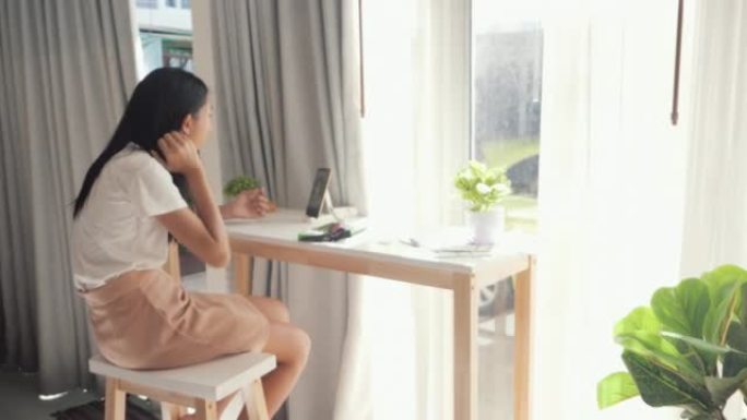亚洲女孩通过智能手机观看电影或病毒视频，并在周末在家的窗户附近吃脆皮海藻。