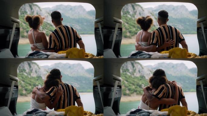 非洲族裔情侣坐在美丽的绿松石湖边的汽车里拥抱