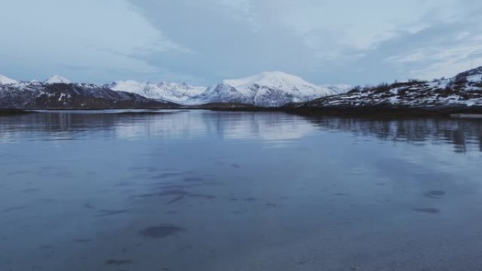 冬天特罗姆瑟海边的风景。积雪覆盖的山脉和杂草