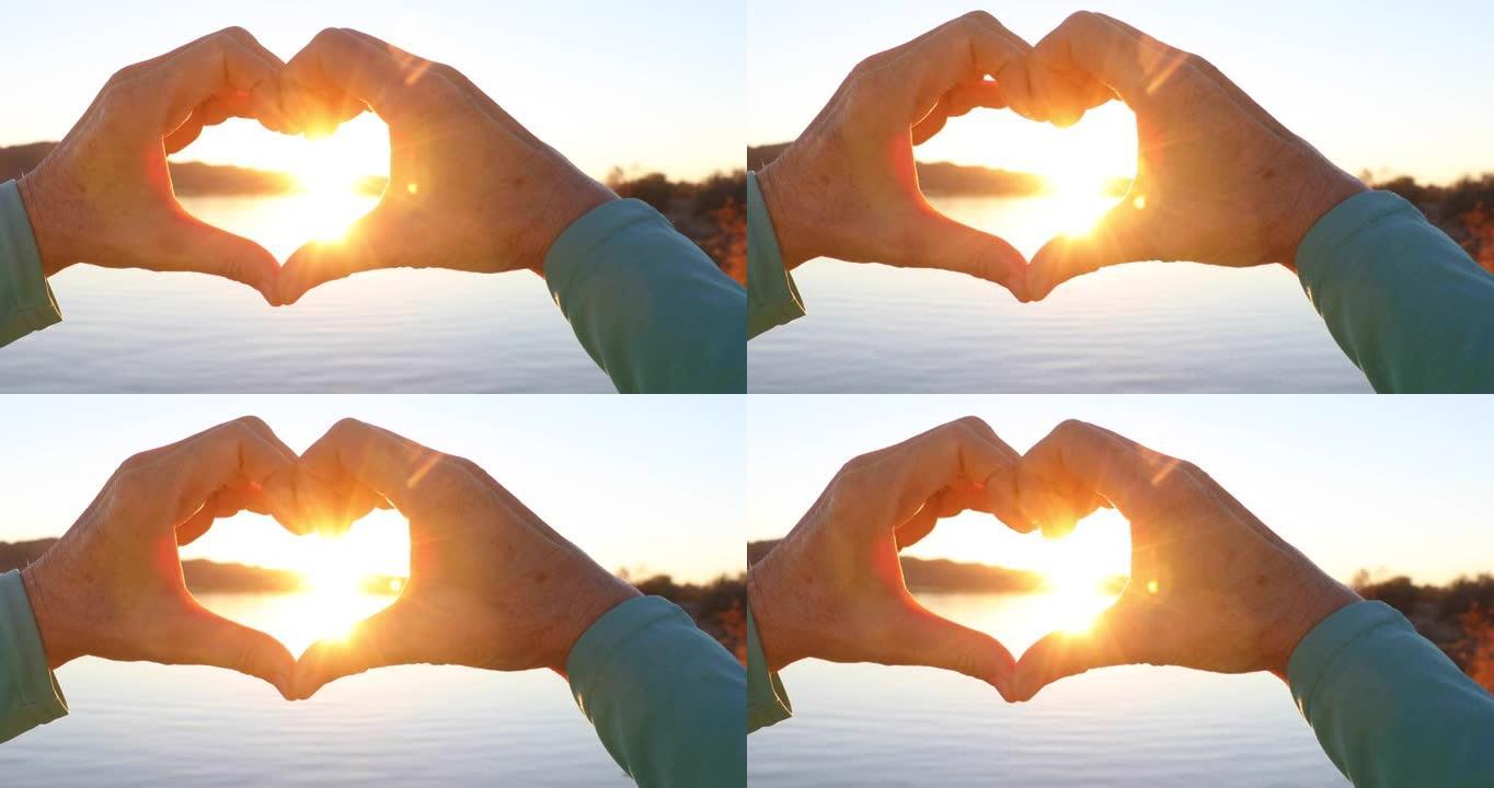 湖泊上形成心形的手的特写视图，日出