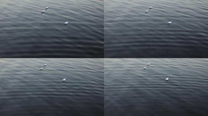 一艘纸船在美丽的日落时漂浮在水中的波浪上。晚上水面上自制的折纸船。特写