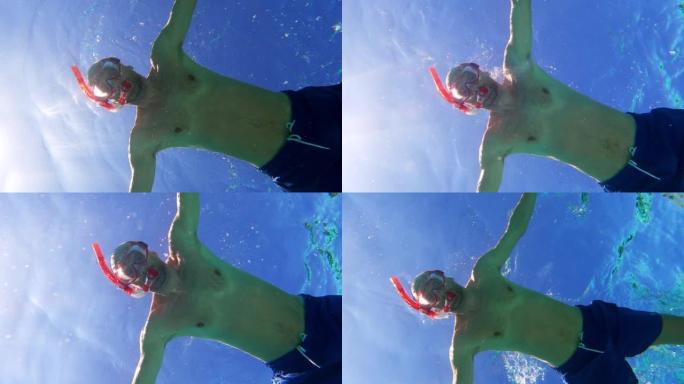 夏天在海里浮潜。男子游泳并潜入水中。水下射击，抬头