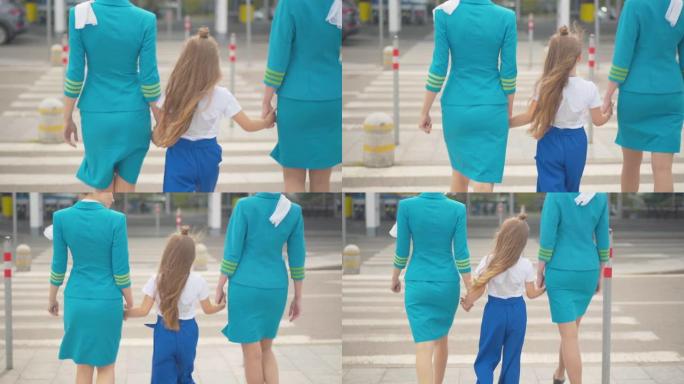 小女孩牵着空姐的手走向机场大门的后视图。专业陪同空姐陪同儿童出发。航空规则概念。