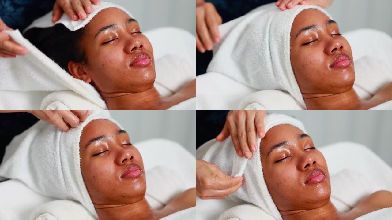面部护理。美丽的非洲裔美国妇女在美容水疗和健康中心进行面部按摩。面部护理和皮肤护理概念。