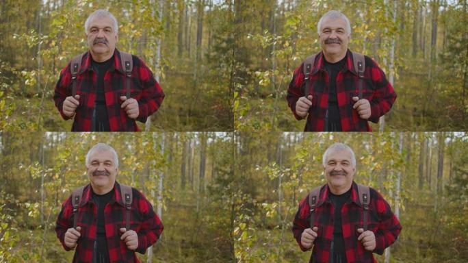 秋天森林里的快乐游客，白天的中等肖像，留着小胡子的白发男人欢快地微笑着