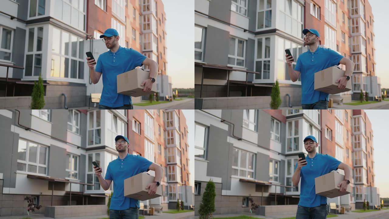 一位戴着圆形眼镜的男性邮递员，随身携带用于交付给客户的盒子，看着他的手机。通过手机搜索送货地址。支付