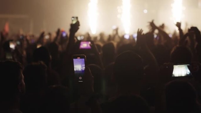 人群在音乐节上欢呼。专注跳舞用智能手机录音的人
