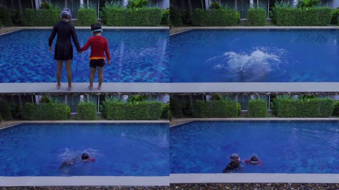 4K，两个亚洲孩子，站在游泳池的边缘，两个手牵手，一起跳水，池水飞溅，两个然后游回游泳池的边缘，再次