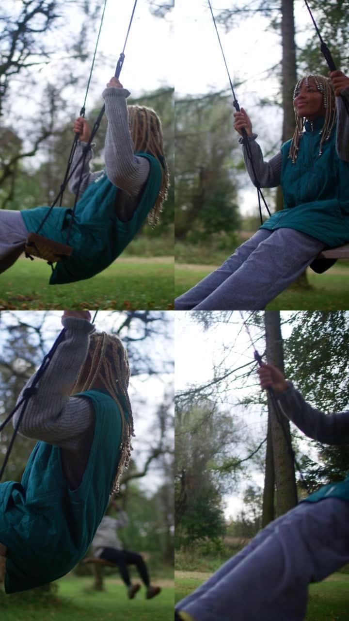 非洲民族少女在秋公园的秋千上来回摇摆。垂直视频
