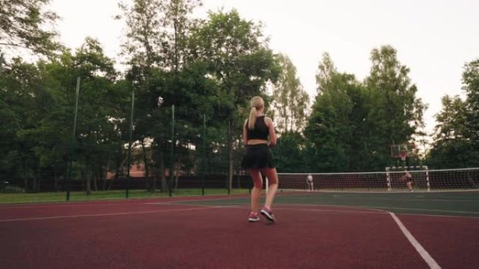 运动女人的运动爱好，女人在户外球场打网球，苗条的金发女人