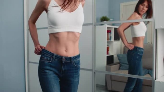 穿着太大牛仔裤的苗条女人展示了她是如何减肥的