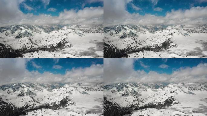 空中飞行穿过山云，飞越美丽的白雪皑皑的山峰和冰川。