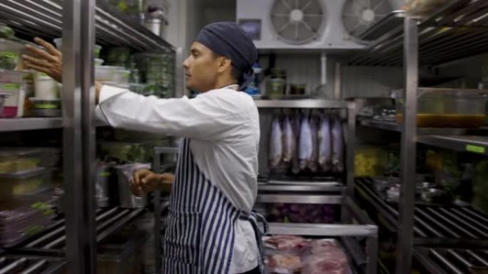 拉丁美洲厨师在一家餐厅工作，在冷藏室寻找一些食材