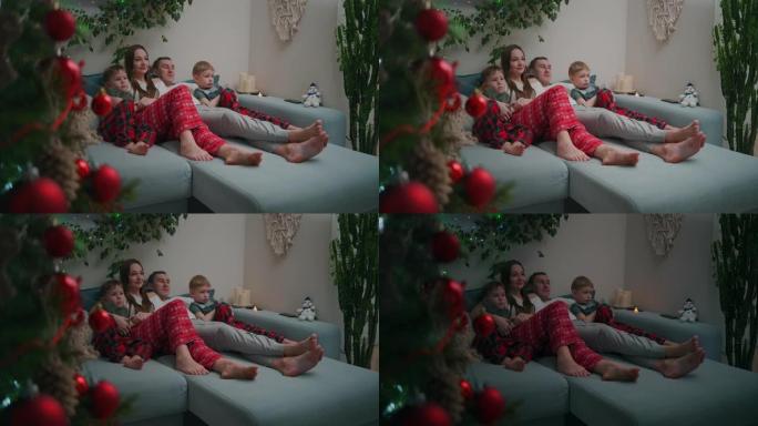 圣诞节期间，高加索家庭坐在沙发上，在家里看电视，装饰公寓内部
