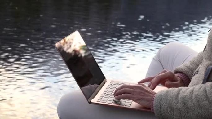 女人在alpine creek的边缘使用笔记本电脑