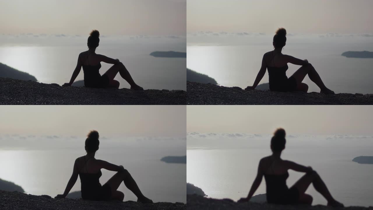非洲民族妇女在悬崖上放松并观看日落