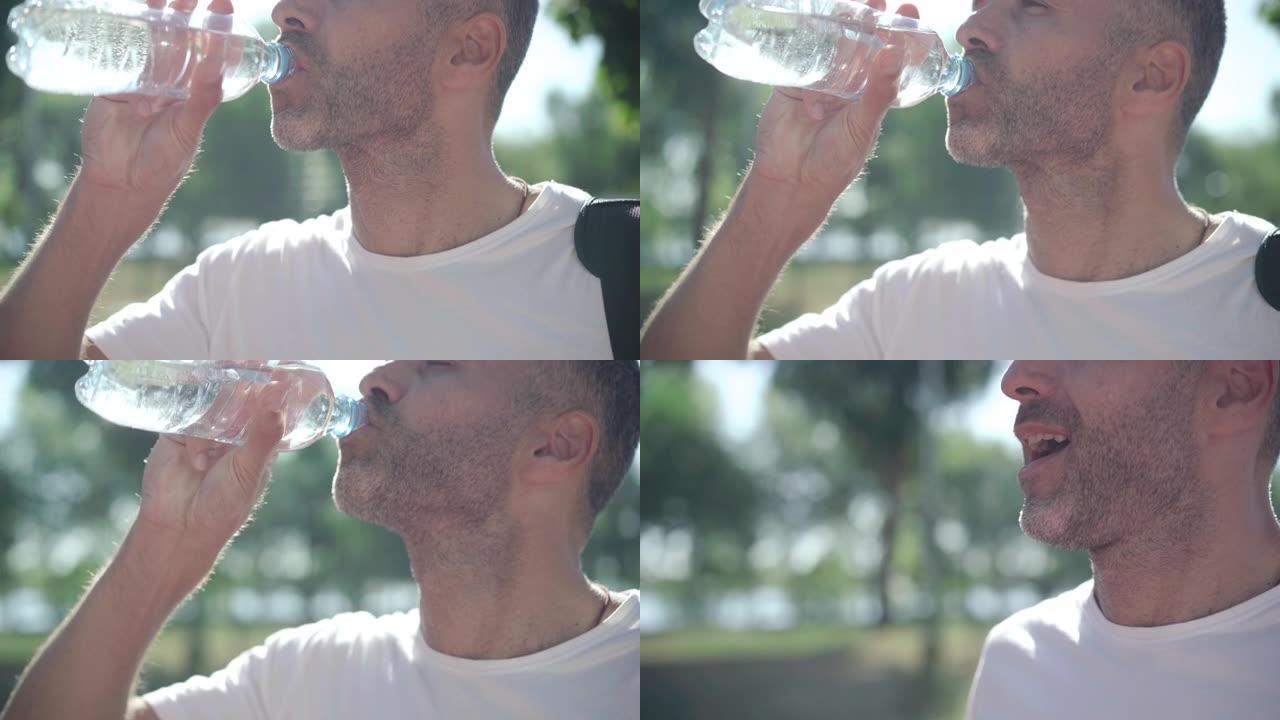 无法识别的高加索成年运动员在阳光照射下在户外喝水并呼吸。疲惫但快乐的白人男子在夏日晨练后休息。