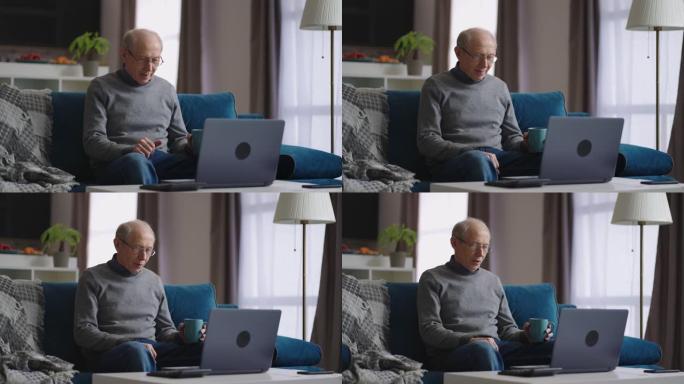 祖父独自一人坐在家里，通过与朋友或家人的视频聊天进行交流，看着笔记本电脑的网络摄像头