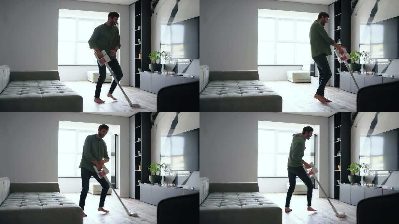 年轻开朗的男人在打扫房间时用吸尘器跳舞