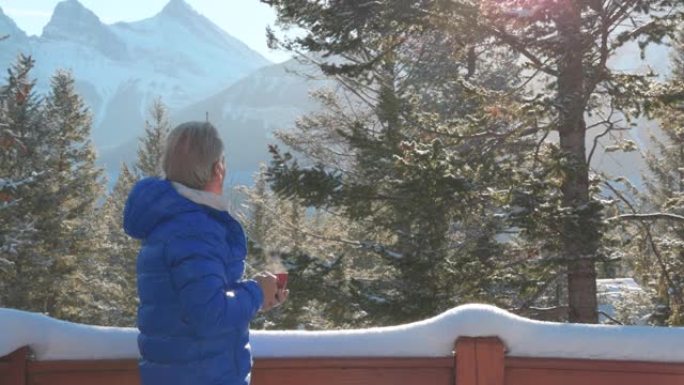 成熟的女人在白雪皑皑的阳台上喝热饮料