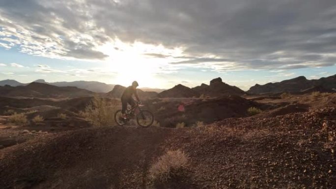 男性山地自行车手在崎terrain的地形上沿着沙漠小路行驶