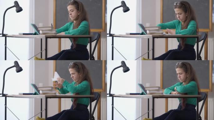 紧张的小人物坐在大学教室的桌子上皱巴巴的纸。侧视肖像悲伤的白人妇女在室内学习写作错误。教育和失败概念