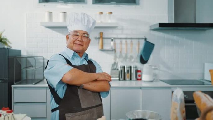 快乐厨师站在厨房里双臂交叉的肖像。