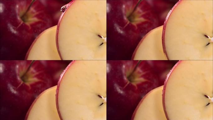 一滴水顺着成熟多汁的红苹果片的表面流下来。慢动作4K