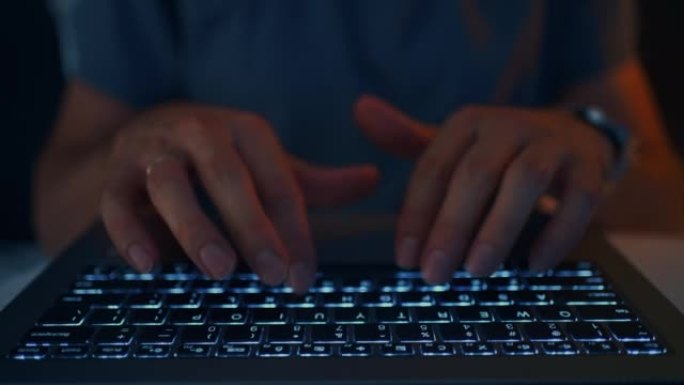 成年男子在夜间使用笔记本电脑，手和键盘的特写视图，上网