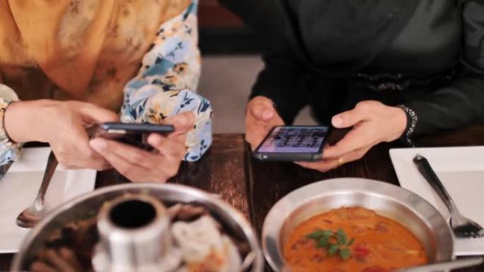 伊斯兰教用手机和朋友一起吃饭，给食物拍照。