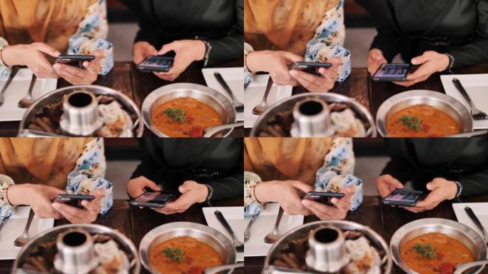 伊斯兰教用手机和朋友一起吃饭，给食物拍照。
