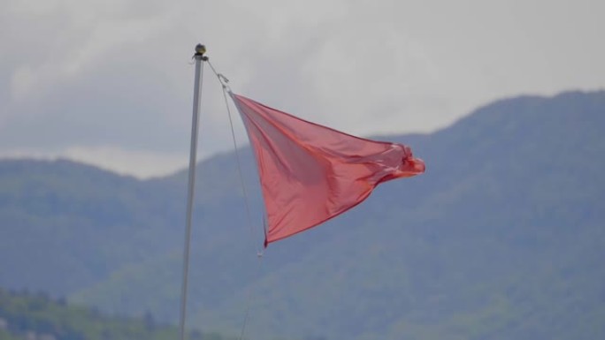 红色海滩警告标志的详细镜头在后面的山上吹动