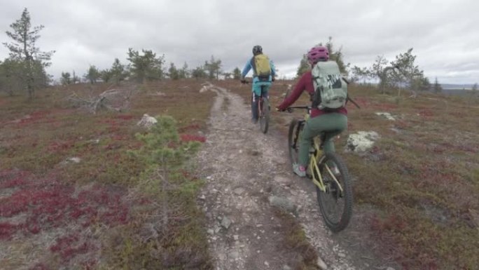 在一片空地上，一男一女骑着山地自行车在小径上拍摄